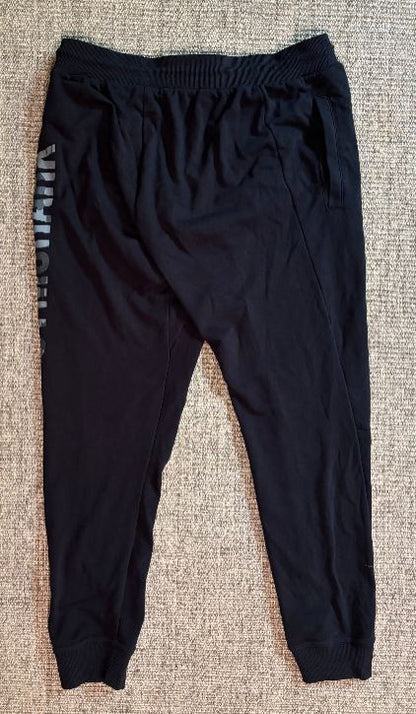 Black jogger pants with a brand logo on a textured surface