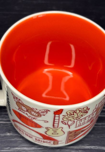 Red mug with white interior and decorative patterns on a dark surface