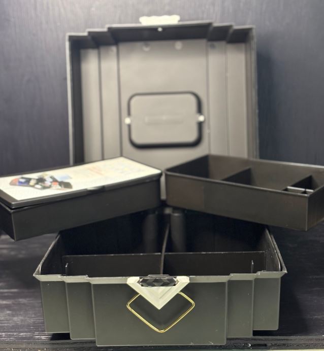 Open black jewelry box with compartments on a dark background