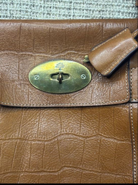 Close-up of a brown leather handbag with a gold clasp.