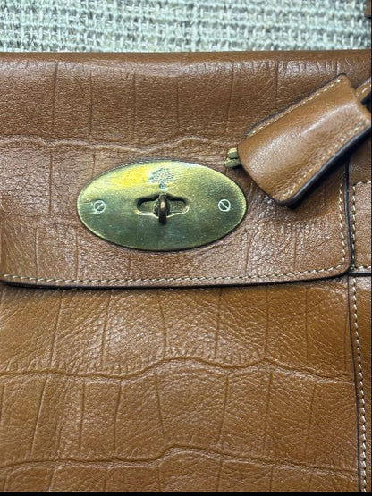 Close-up of a brown leather handbag with a gold clasp.