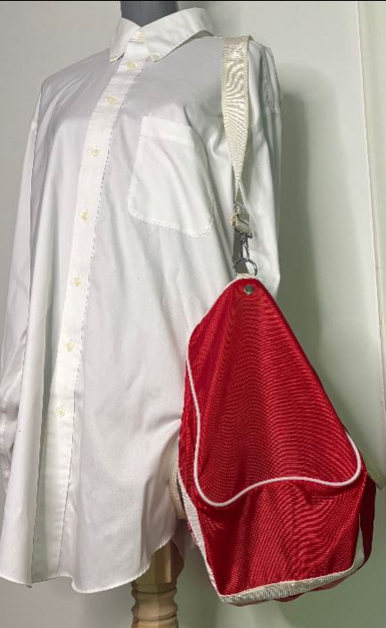 Red bag with white trim on a mannequin wearing a white shirt.