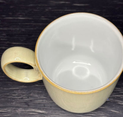 Ceramic mug with a gold rim and handle on a dark surface