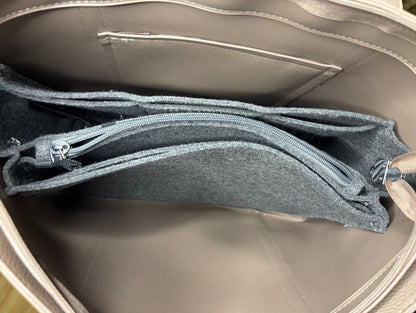 Open beige handbag with gray interior showing zippers and fabric texture.