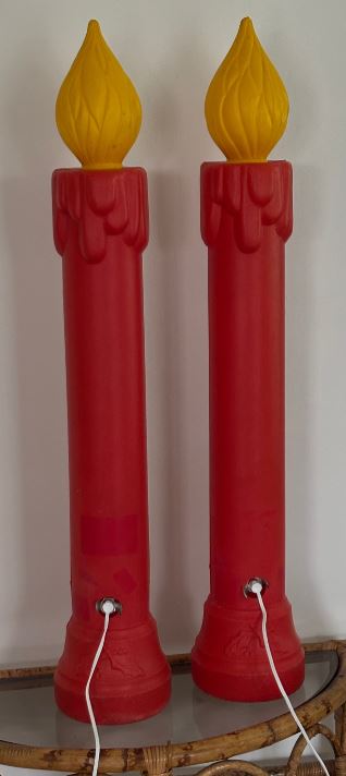 Two red candle-shaped lamps with yellow flame tops on a white background