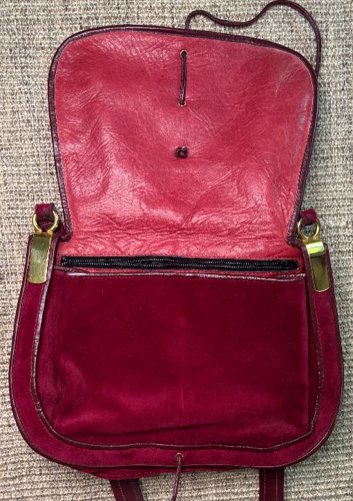 Red leather bag with gold zippers on a textured surface