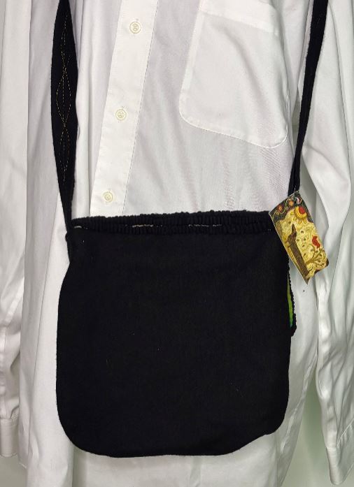 Black crossbody bag with a visible brand tag on a white shirt.