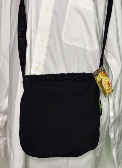 Black crossbody bag with a visible brand tag on a white shirt.