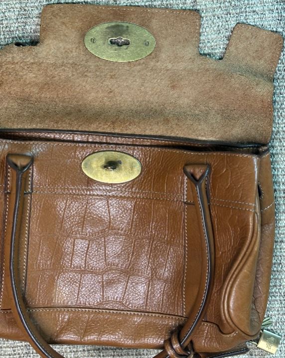 Brown leather bag with gold accents on a textured surface