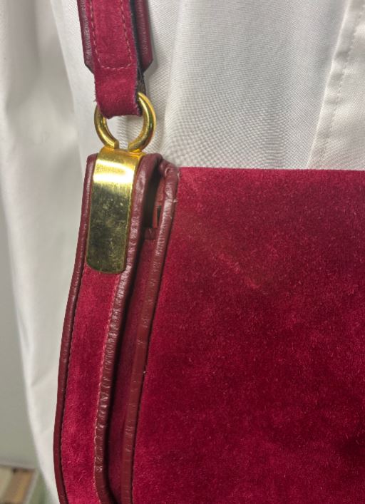 Close-up of a red handbag with a gold clasp on a white background