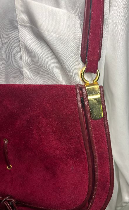 Close-up of a red handbag with a gold clasp on a light gray background