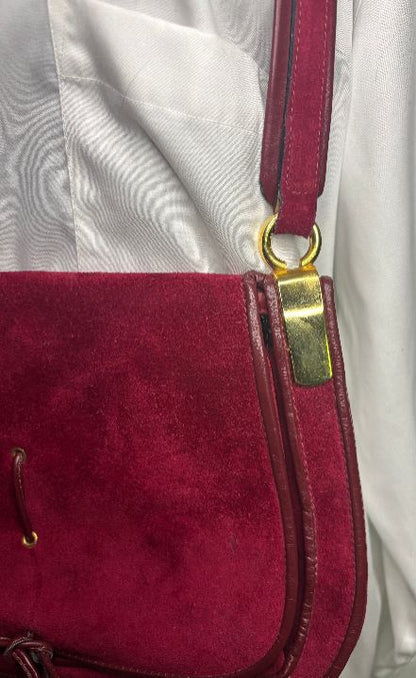 Close-up of a red handbag with a gold clasp on a light gray background
