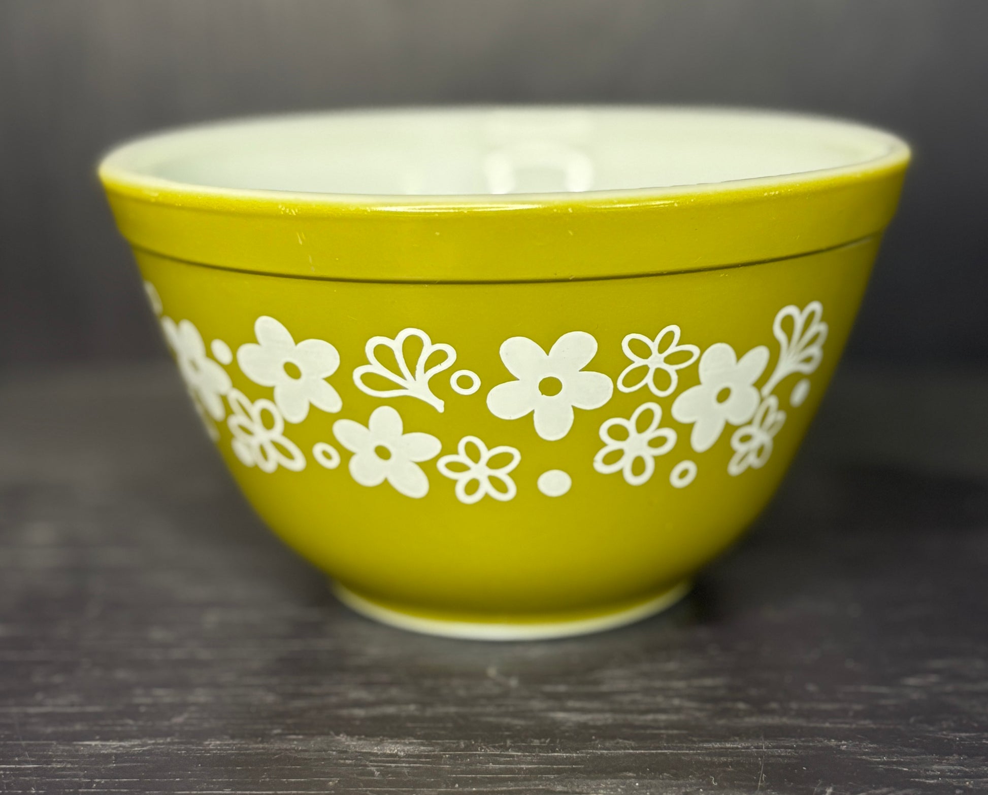 Green bowl with white floral pattern on a dark surface