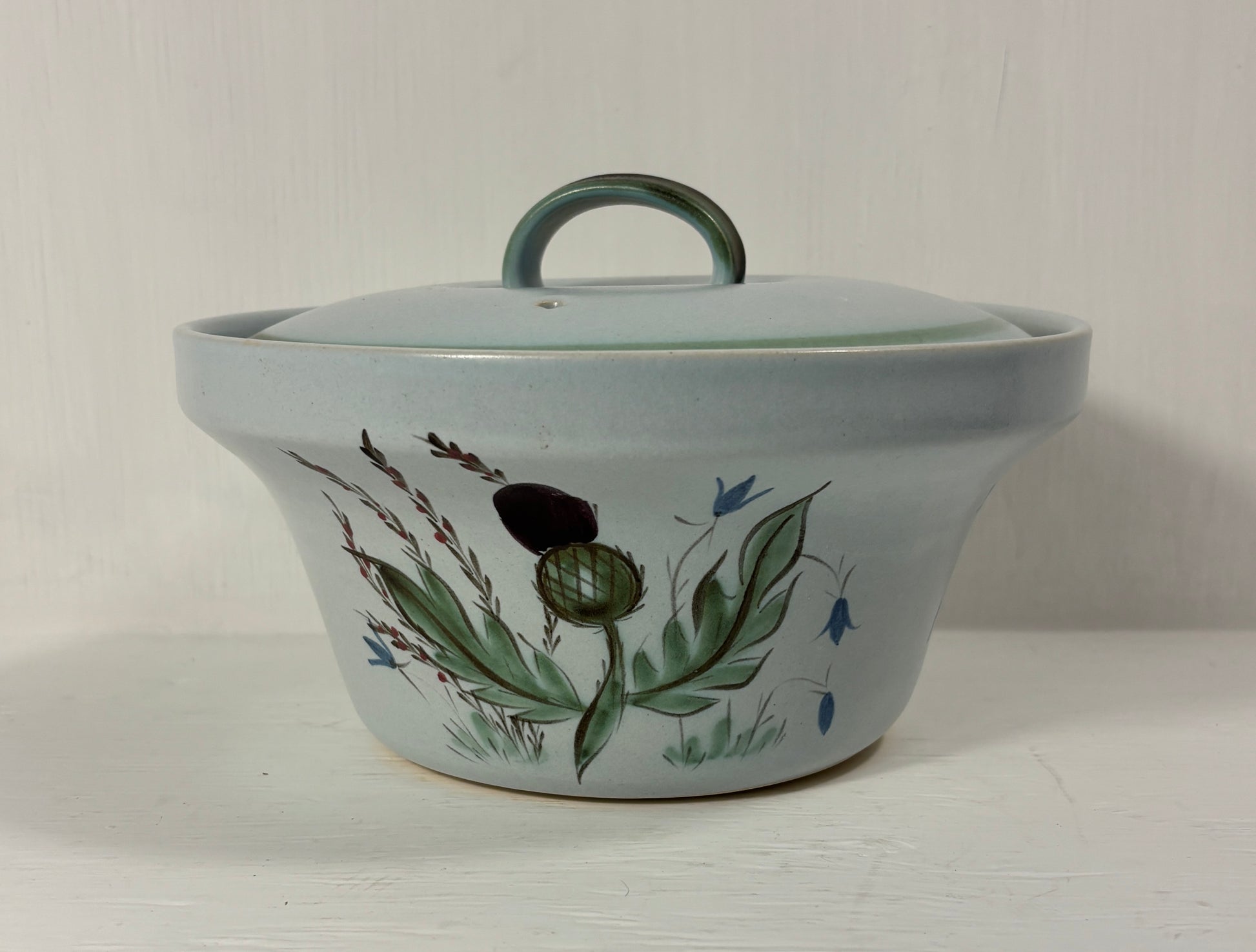 Ceramic pot with lid and floral design on a white background
