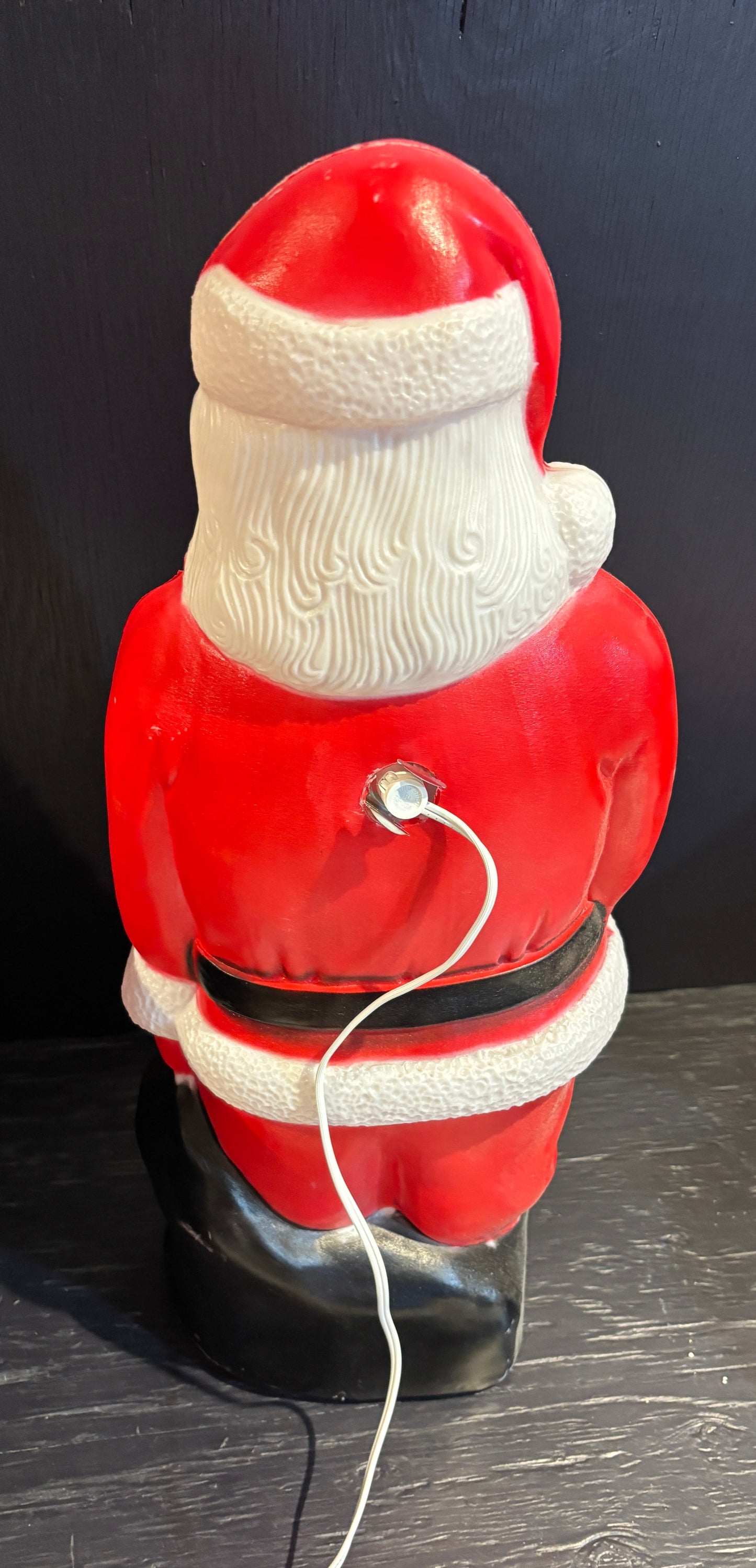 Vintage-style Santa Claus figure with a power cord on a dark background