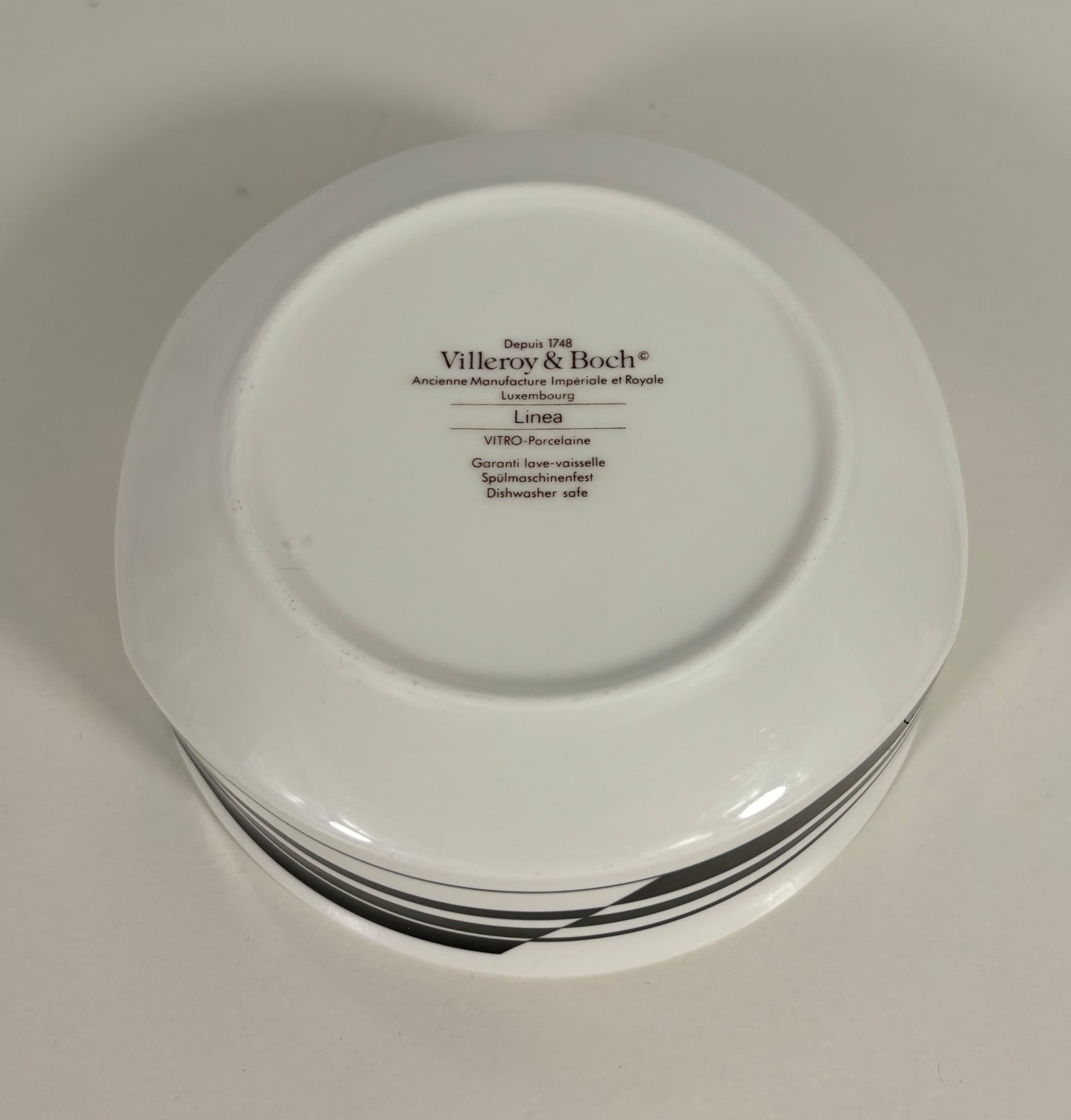 Stack of white plates with 'Villeroy & Boch' branding on a light gray background
