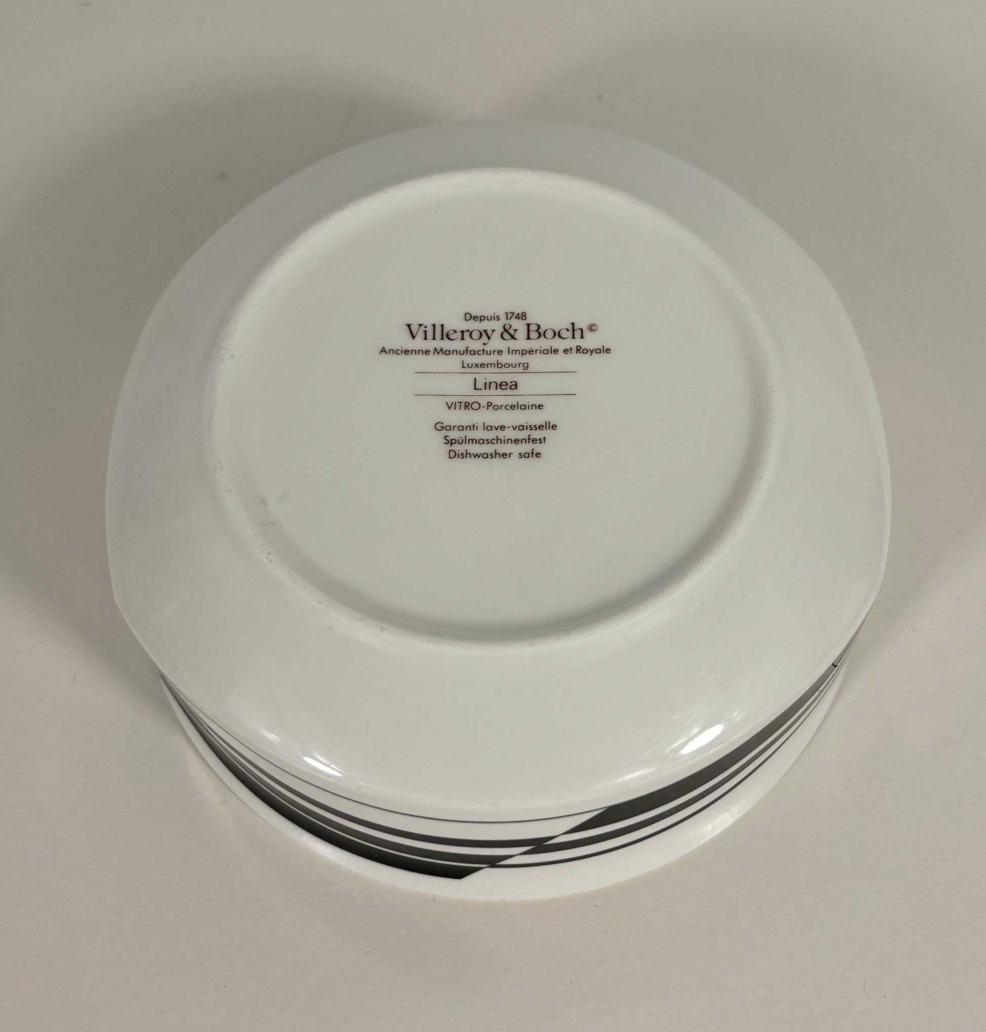 Stack of white plates with 'Villeroy & Boch' branding on a light gray background