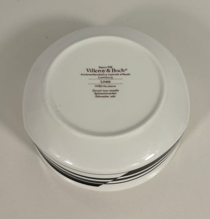 Stack of white plates with 'Villeroy & Boch' branding on a light gray background