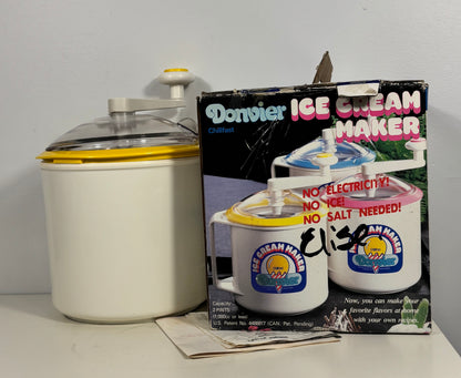 A vintage Donvier ice cream maker set displayed on a tabletop against a plain wall, including the creamer container, the retail box, and handwritten price marking on the package.