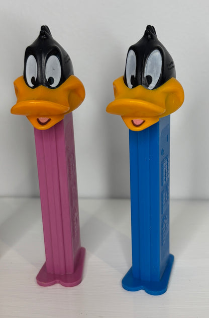 Two PEZ dispensers shaped like cartoon characters on a white background
