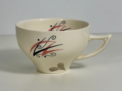 White ceramic mug with black and red abstract design on a gray background