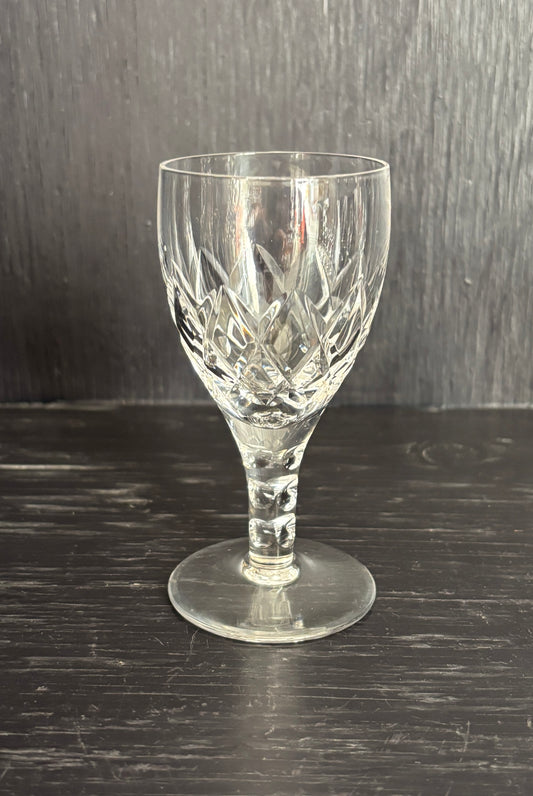 Clear glass wine glass with cut patterns on a dark wooden surface