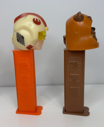Two PEZ dispensers, one with a character head and orange base, the other with a brown base.