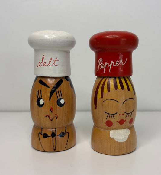 Wooden salt and pepper shakers with faces on a white background