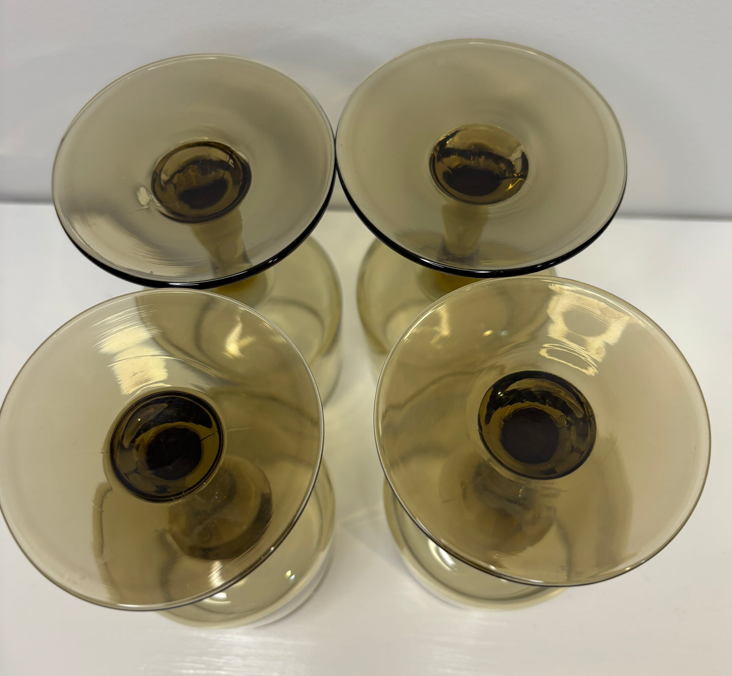 Four transparent glass candle holders on a white surface with a light gray background