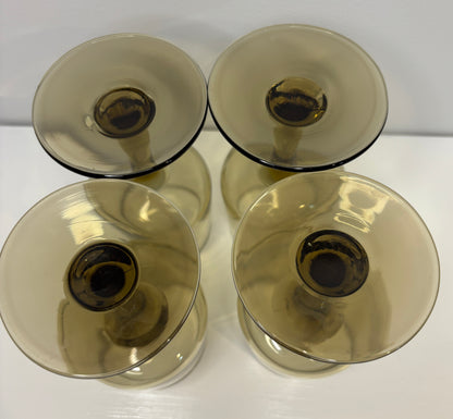 Four transparent glass candle holders on a white surface with a light gray background