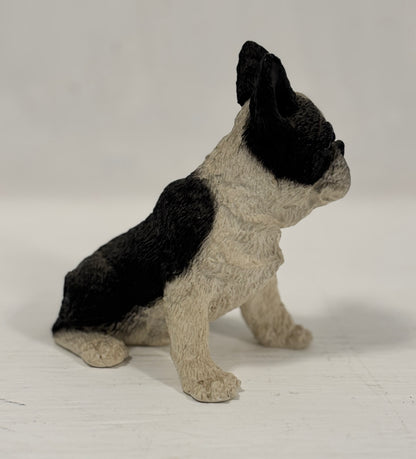 Statue of a sitting dog with black and beige fur on a white background