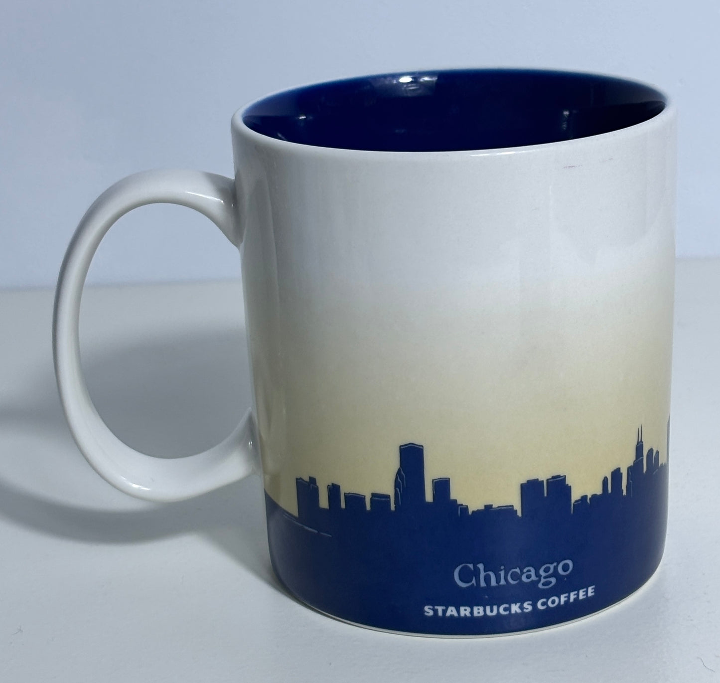 White mug with blue interior and Chicago skyline design on a light gray background