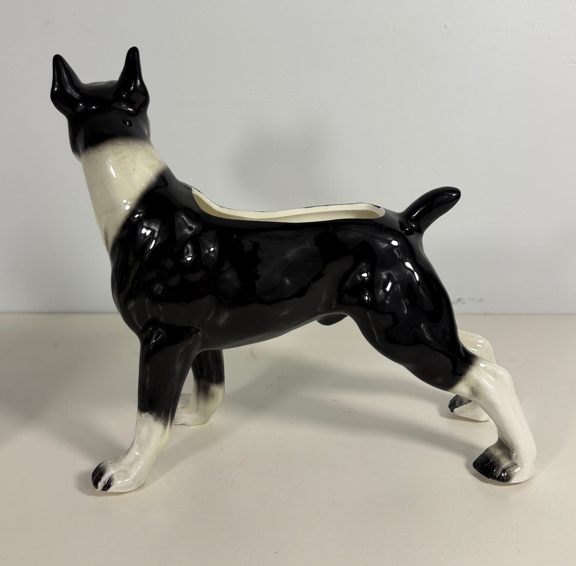 Ceramic dog-shaped planter with black and white design on a plain background