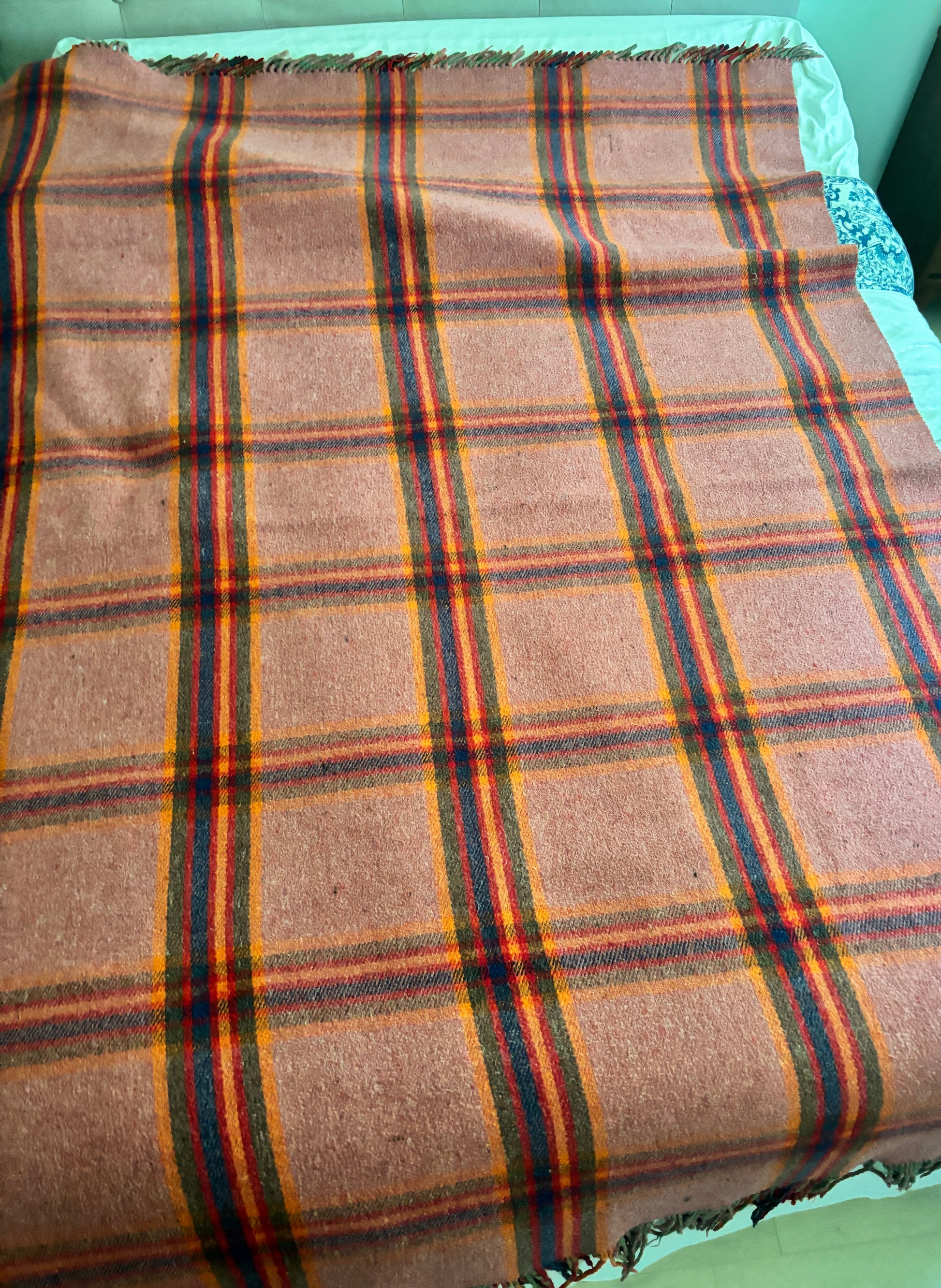 Plaid wool blanket with brown, red, and blue pattern on a green surface