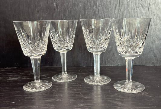 Four crystal wine glasses on a dark surface with a dark background