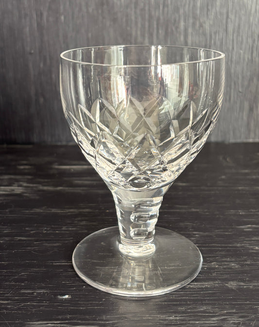 Clear glass goblet with intricate cut patterns on a dark surface