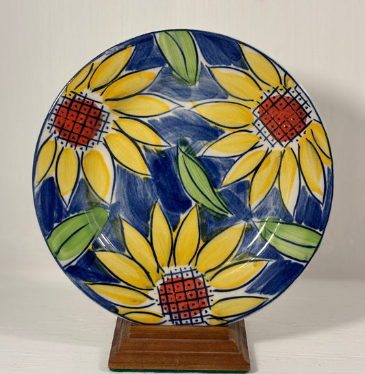 Ceramic plate with sunflower design on a stand against a white background