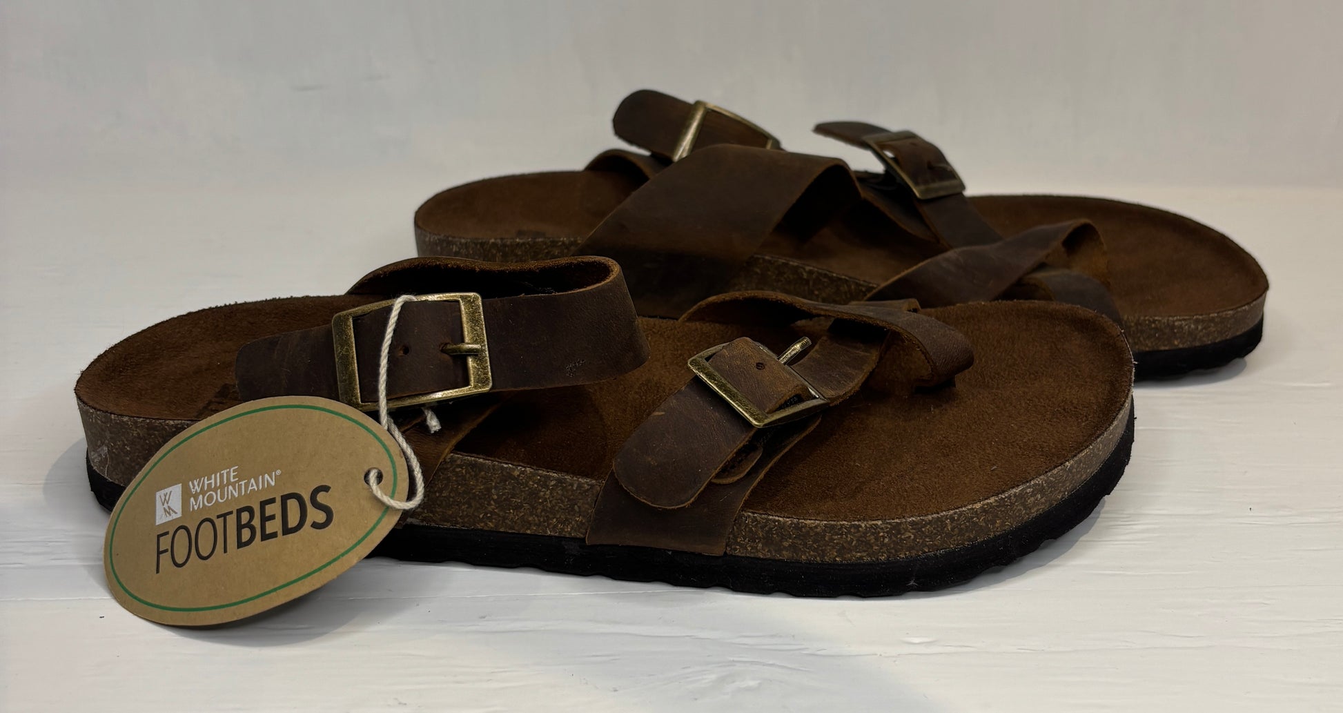 Brown sandals with a visible brand tag on a white background