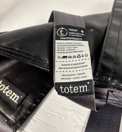 Close-up of a 'totem' brand label on a black bag.