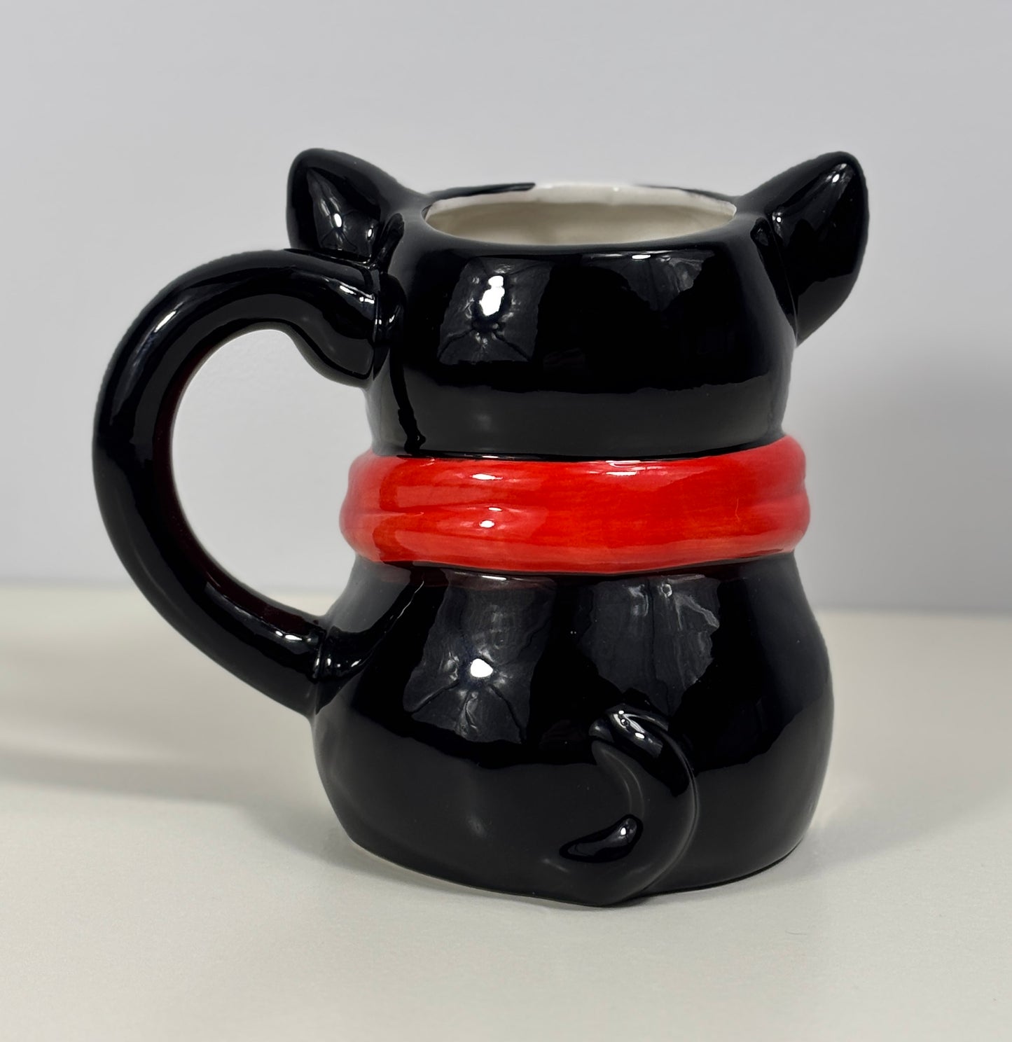Black dog-shaped mug with a red collar on a white background