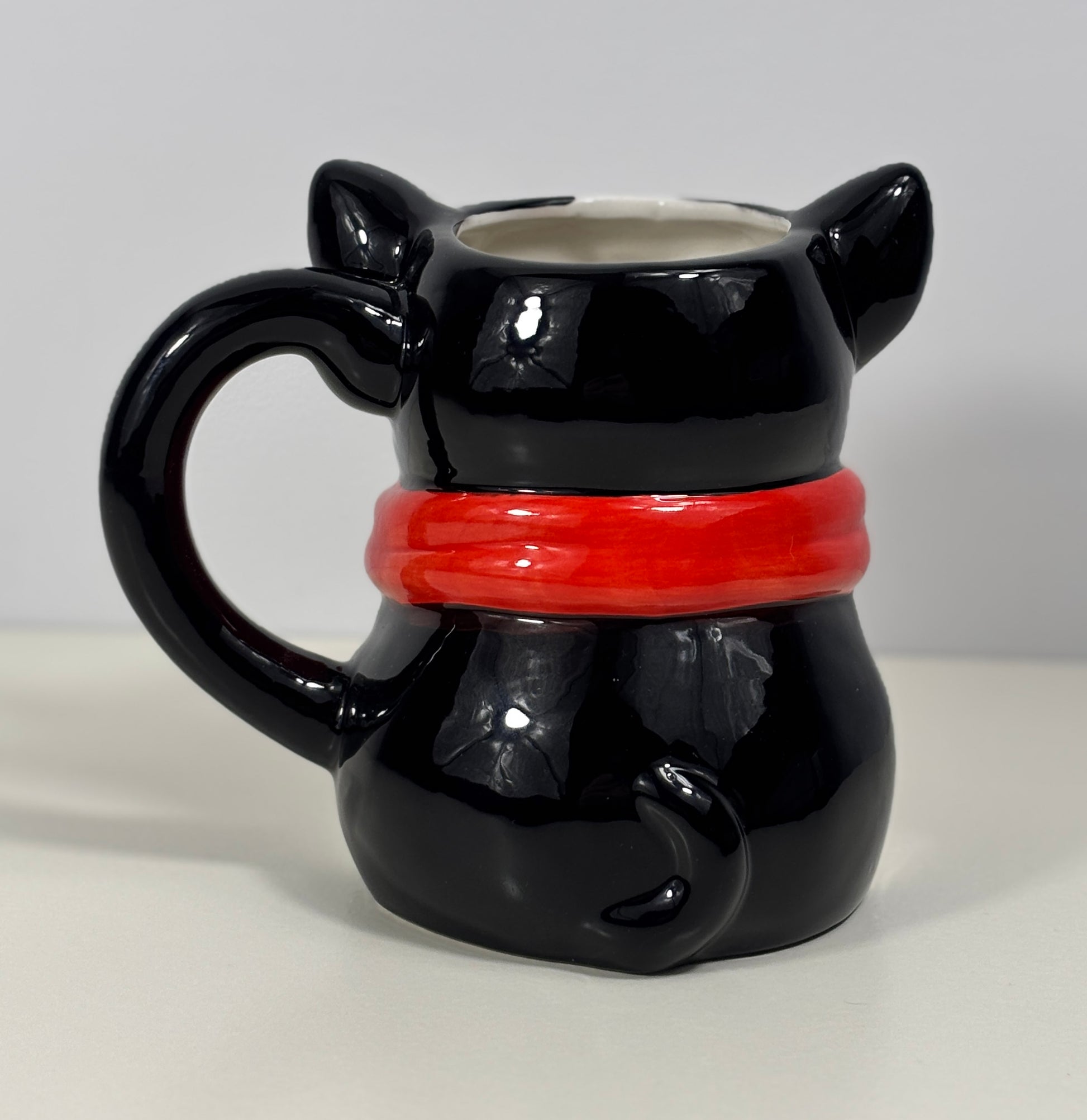 Black dog-shaped mug with a red collar on a white background