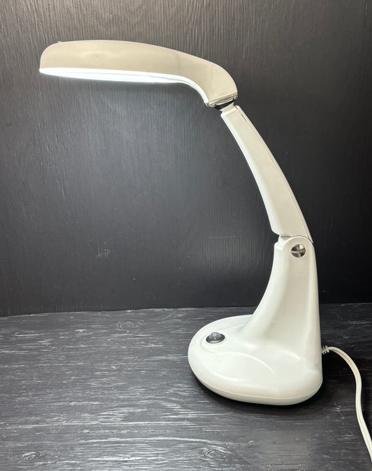 White desk lamp on a dark surface with a dark background