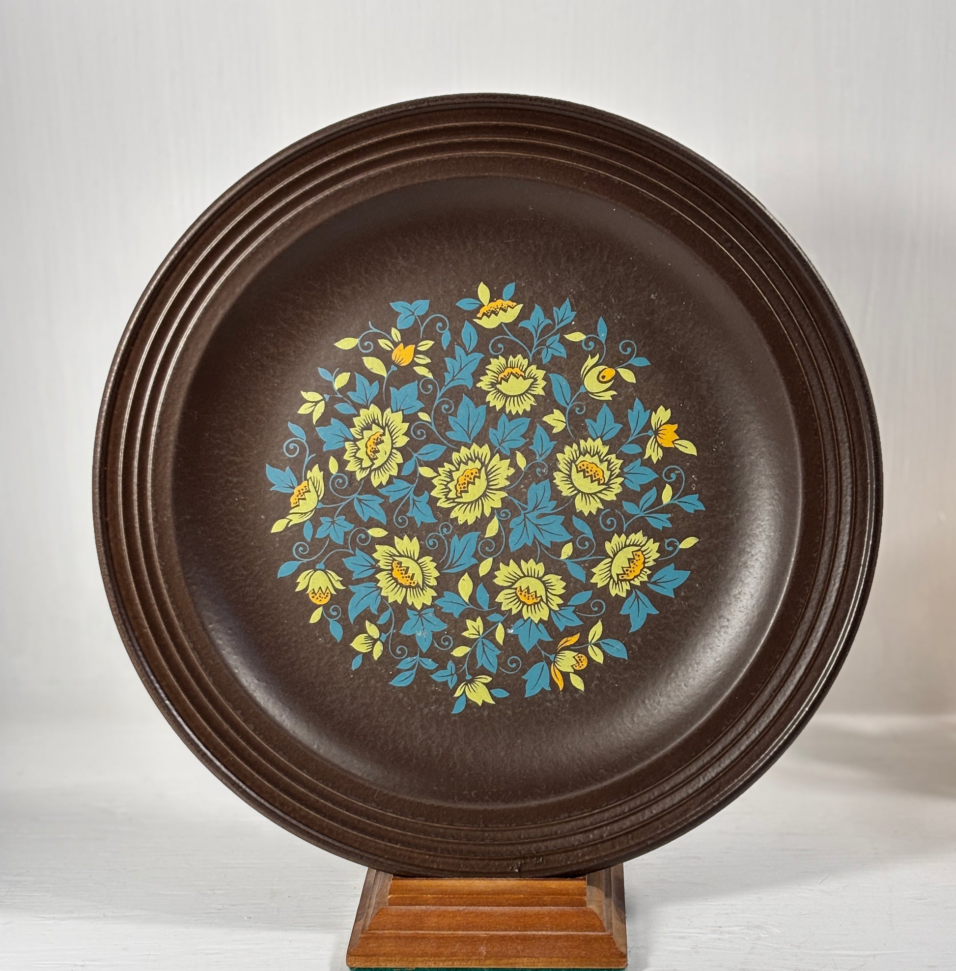 Decorative plate with floral design on a stand against a white background