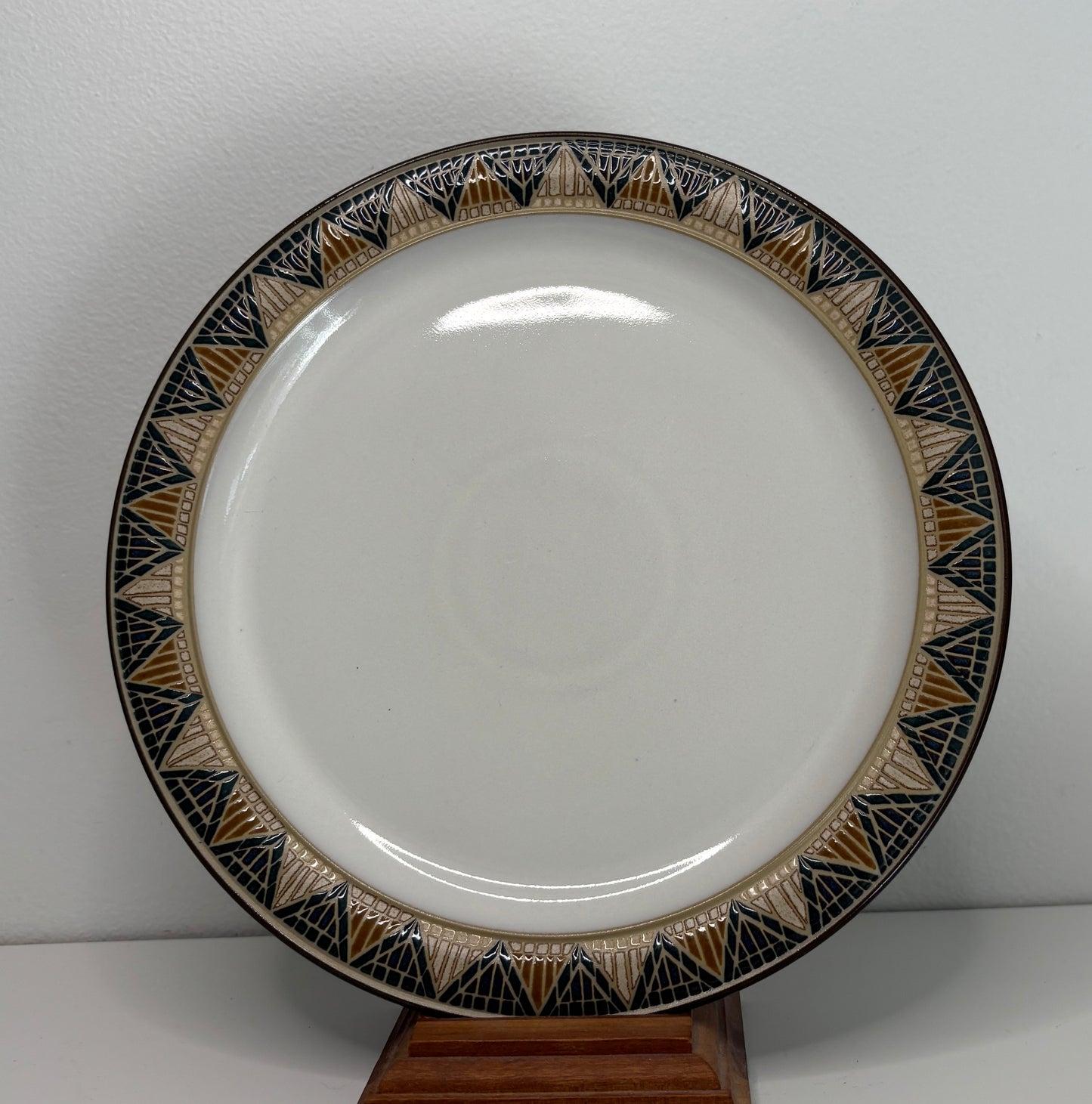 White plate with decorative black and gold rim on a stand against a white background