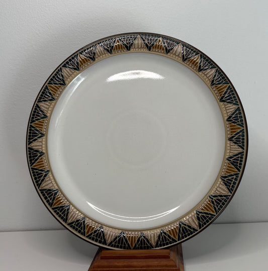 White plate with decorative black and gold rim on a stand against a white background