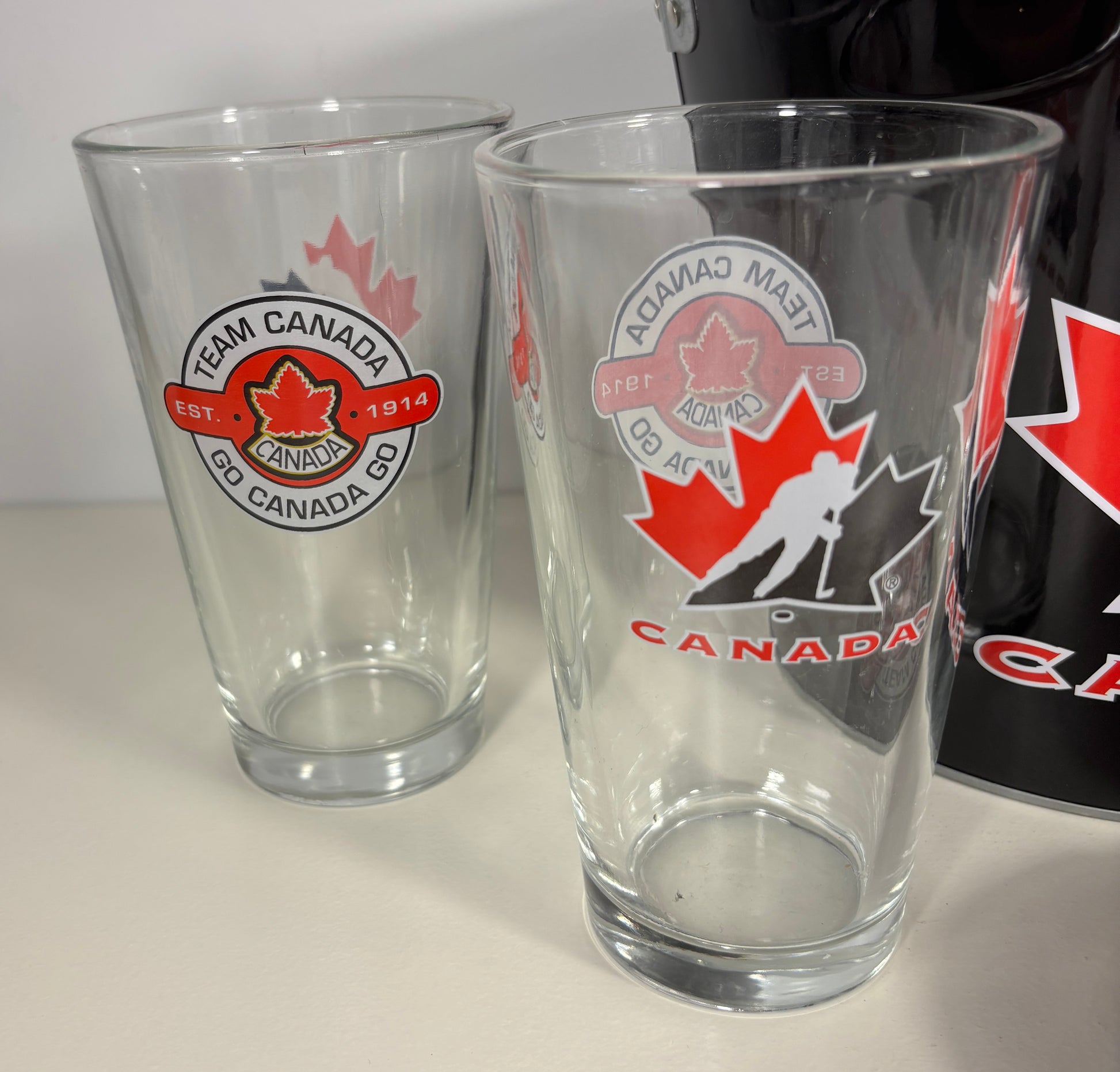 Two clear glasses with Team Canada logos on a white surface.