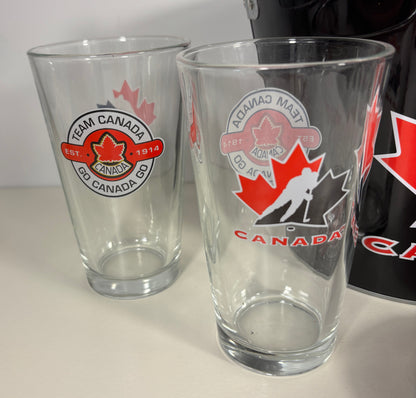 Two clear glasses with Team Canada logos on a white surface.