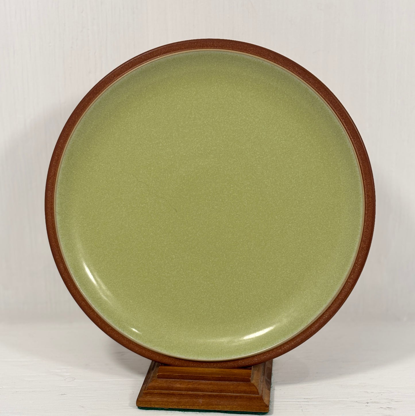 Green ceramic plate with wooden rim on a white background