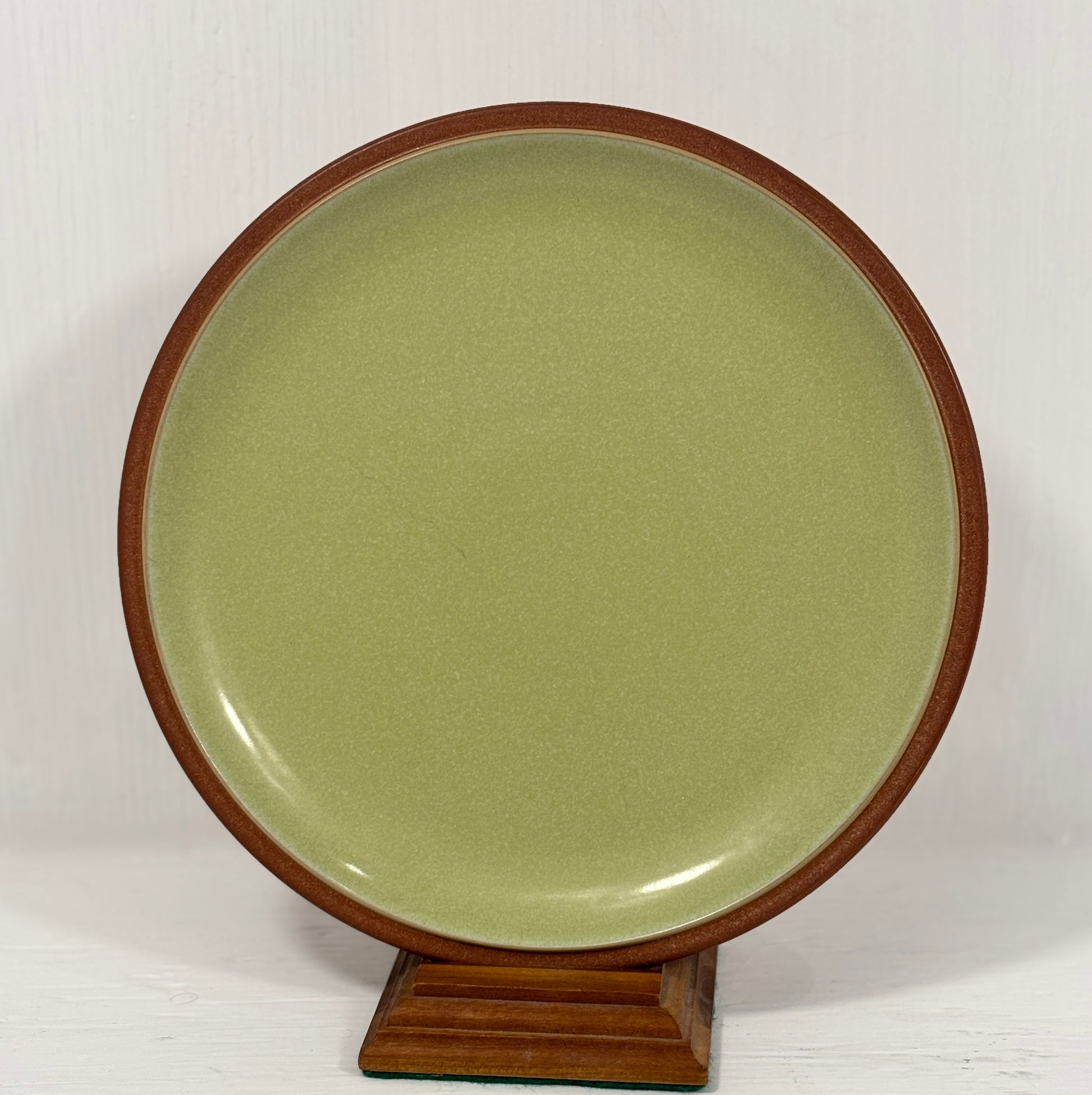 Green ceramic plate with wooden rim on a white background