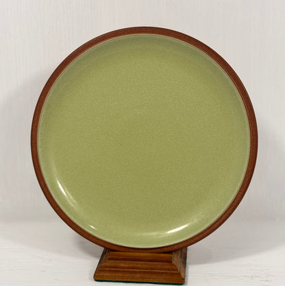 Green ceramic plate with wooden rim on a white background